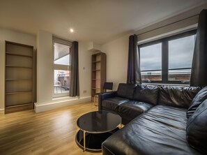Una sala de estar moderna con un sofá de cuero, una mesa de centro redonda y una estantería.
