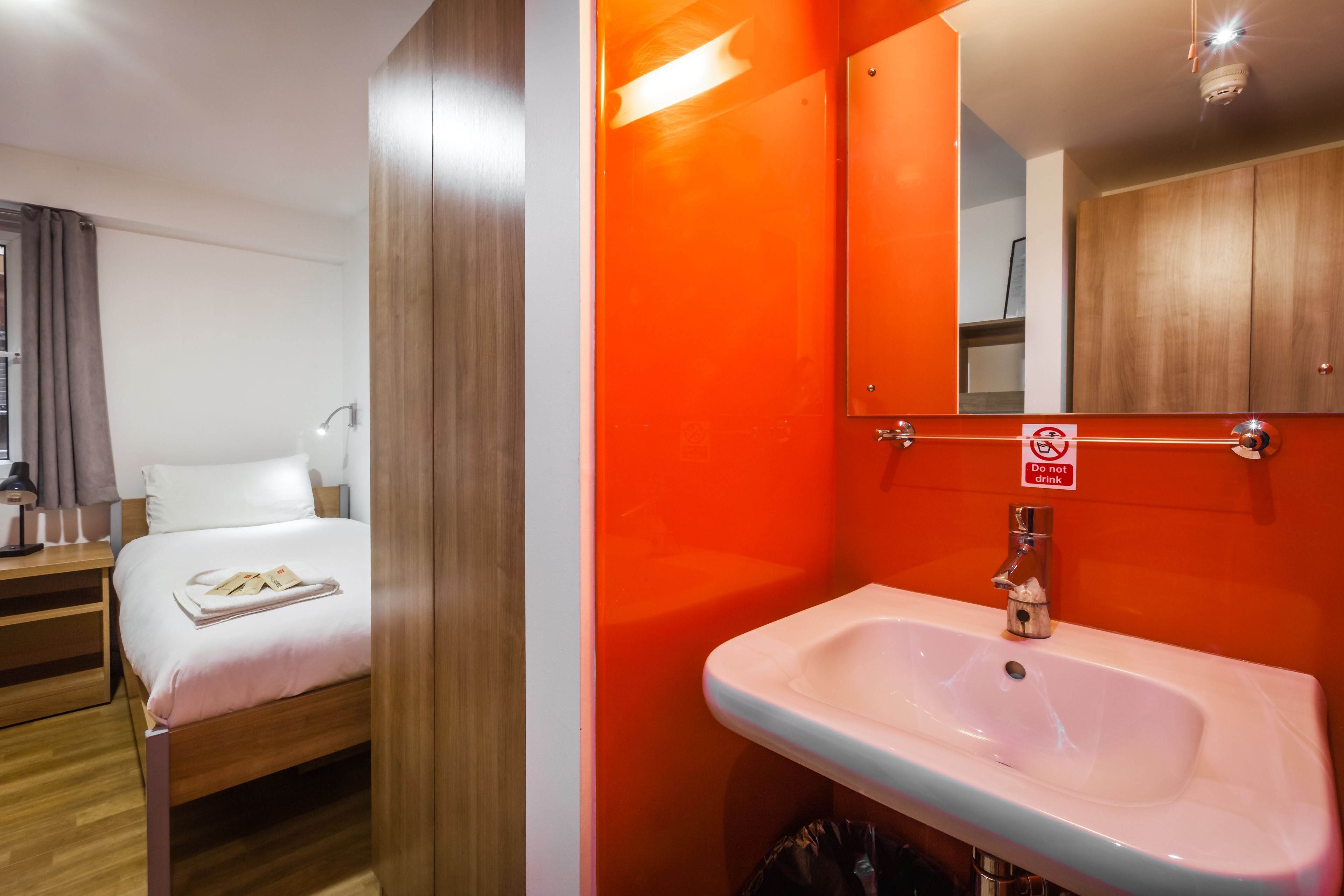 Une chambre d’hôtel avec un lit, un lavabo et un miroir.