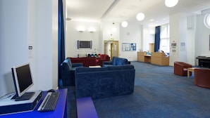 Una biblioteca moderna con asientos azules, una estación de computadoras y un mostrador de recepción.
