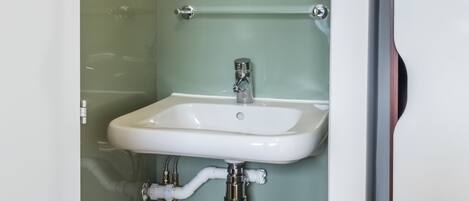 A bathroom with a white sink, a mirror, and a shower enclosure.