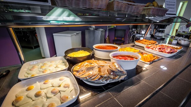 Un bufé con diversas opciones de comida, incluyendo huevos, carnes y salsas.