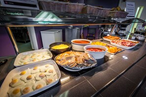 Un buffet proposant une variété de plats, notamment des œufs, des viandes et des sauces.
