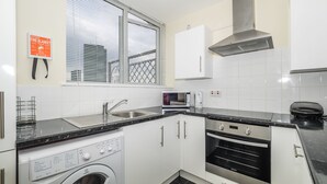 Una cocina moderna con un lavamanos de acero inoxidable, un microondas, un horno empotrado y una lavadora.