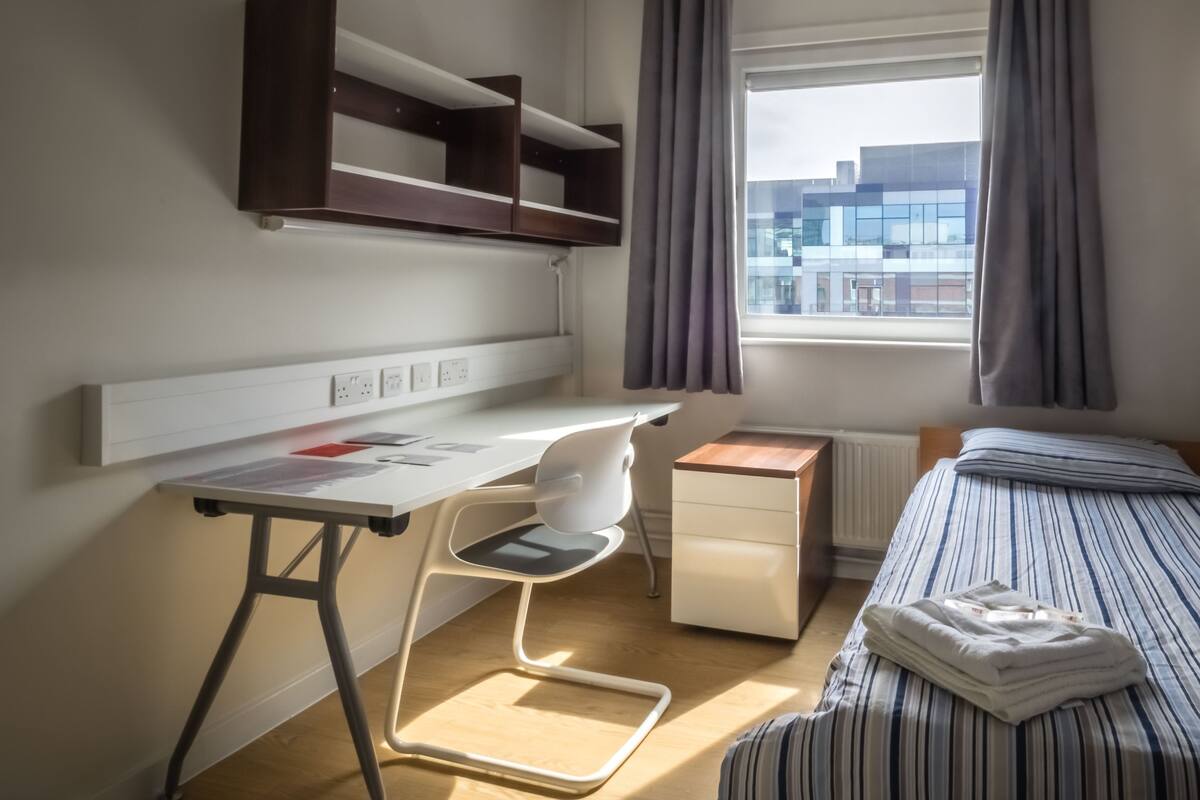 Un dormitorio moderno con escritorio, silla y cama.