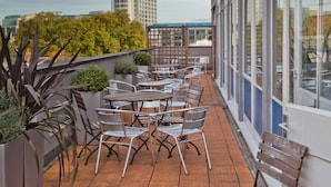 Terraza en la azotea con mobiliario exterior, plantas en macetas y vistas del horizonte urbano.