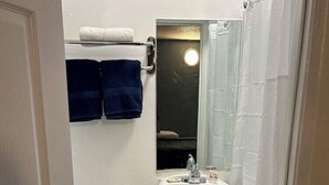 Pieni, siisti kylpyhuone, jossa on wc, pesuallas ja peili pesualtaan yläpuolella.