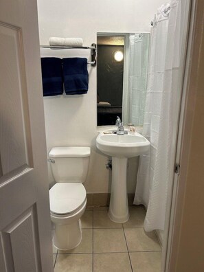 A small, clean bathroom with a toilet, sink, and a mirror above the sink. - Budget Inn Hollywood (Hollywood)