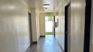 A long, narrow hallway with a wooden floor and beige walls, leading to an exit door. - Budget Inn Hollywood (Hollywood)