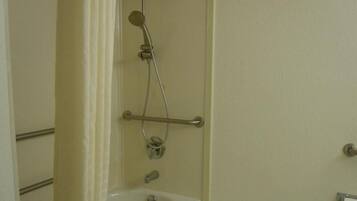 Un baño con lavamanos blanco, cabezal de ducha de mano y barra de apoyo.