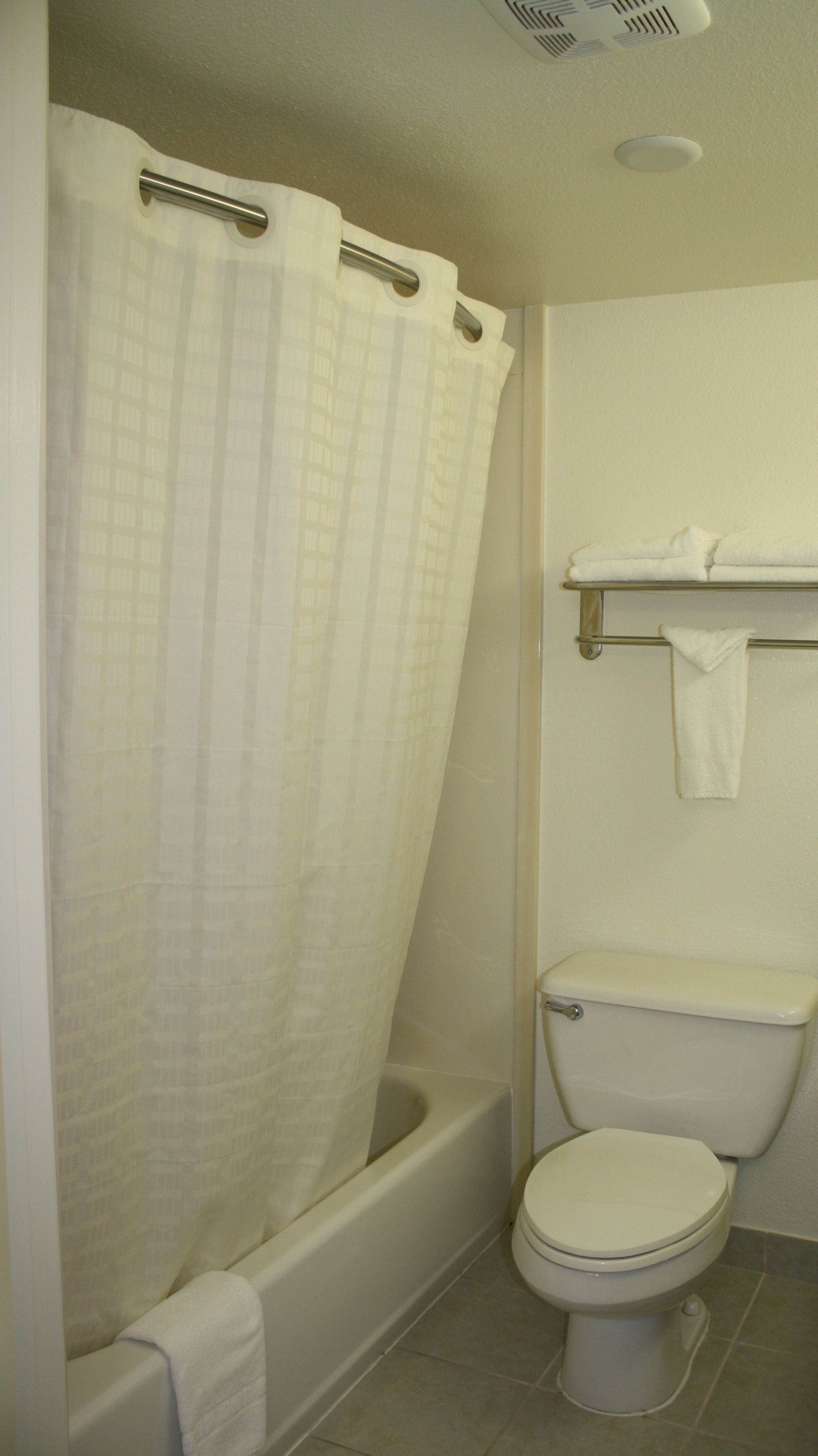 Un baño con bañera, inodoro y perchero para toallas.