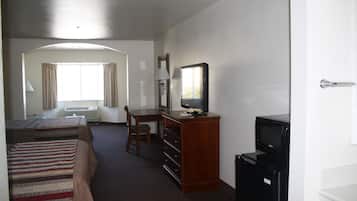 Een hotelkamer met twee bedden, een bureau, een televisie en een koelkast.