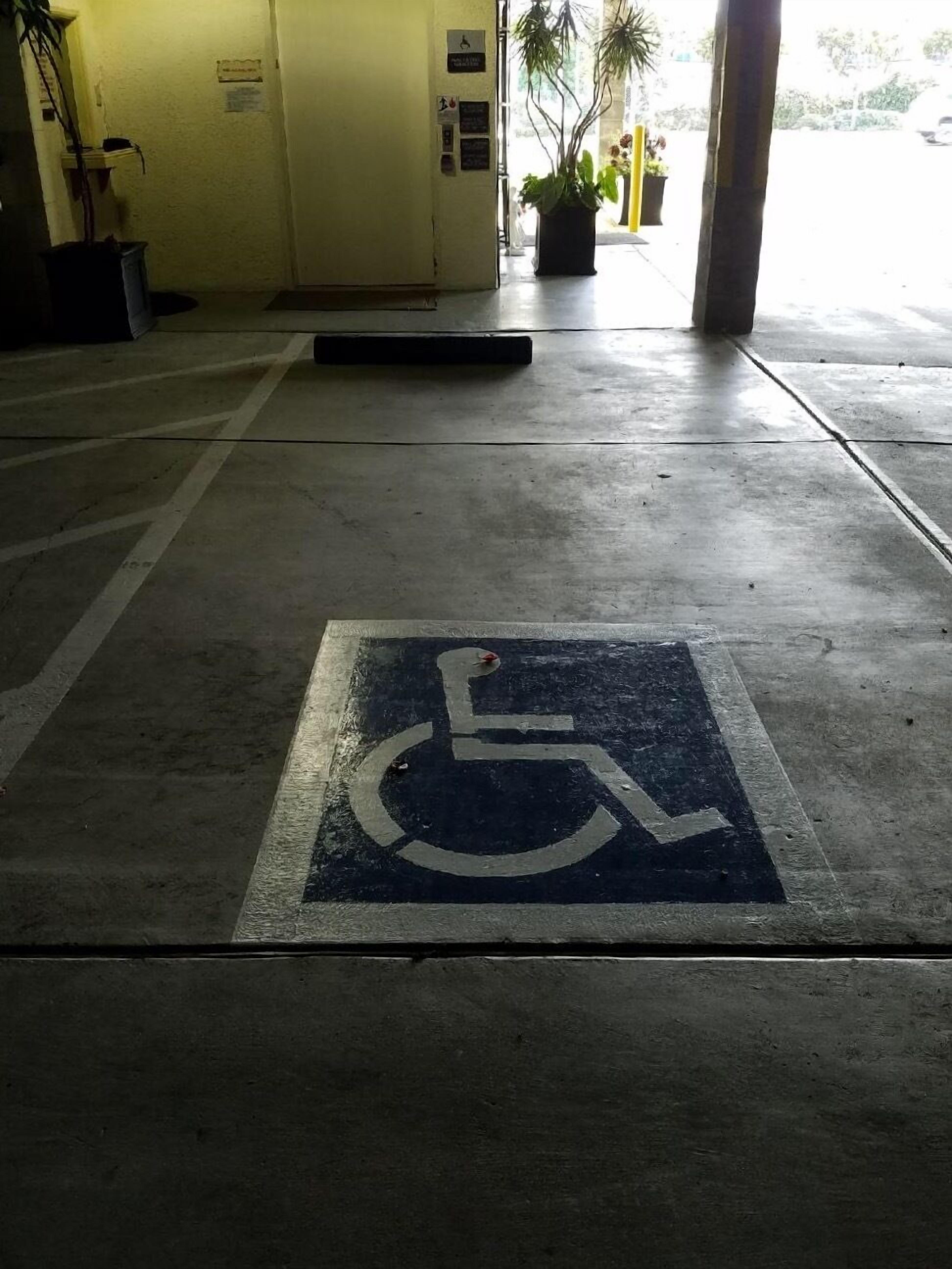 Une place de stationnement adaptée aux fauteuils roulants, avec le symbole international d’accès pour personnes handicapées peint au sol.
