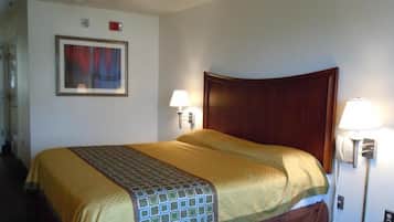 A hotel room with a large bed, two bedside lamps, a telephone, and a framed picture on the wall.