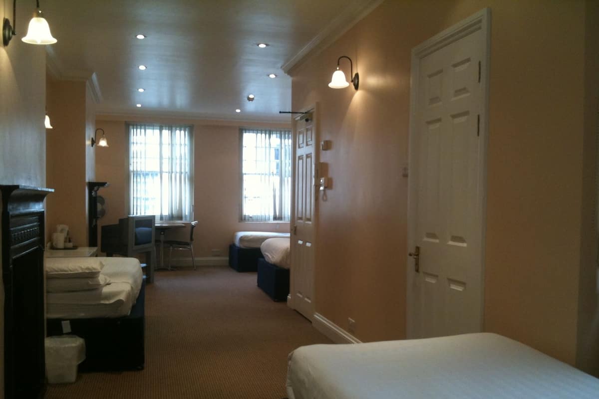 A hotel room with two beds, a desk, a chair, and a television.