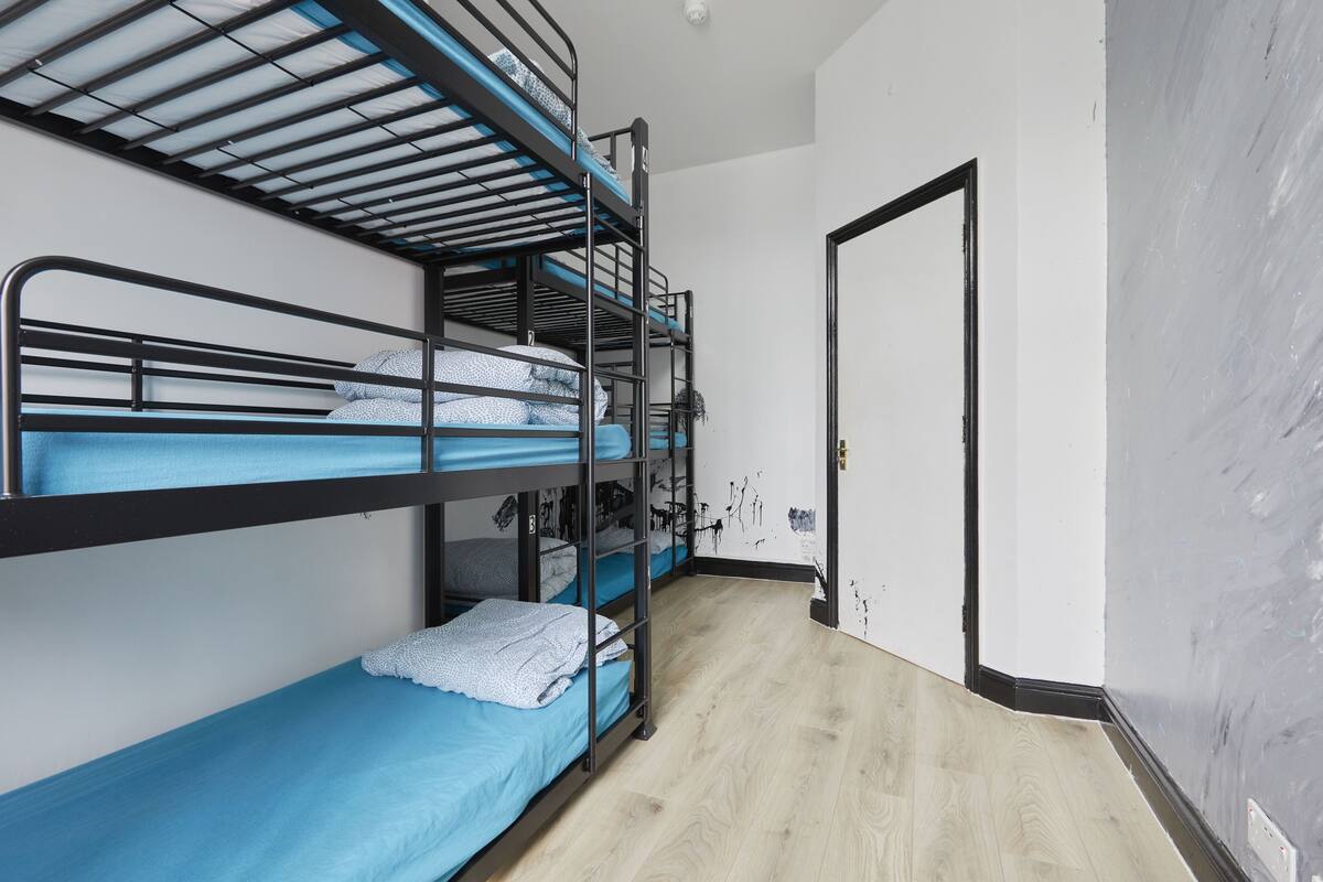 A bunk bed room with a wooden floor and a white door.