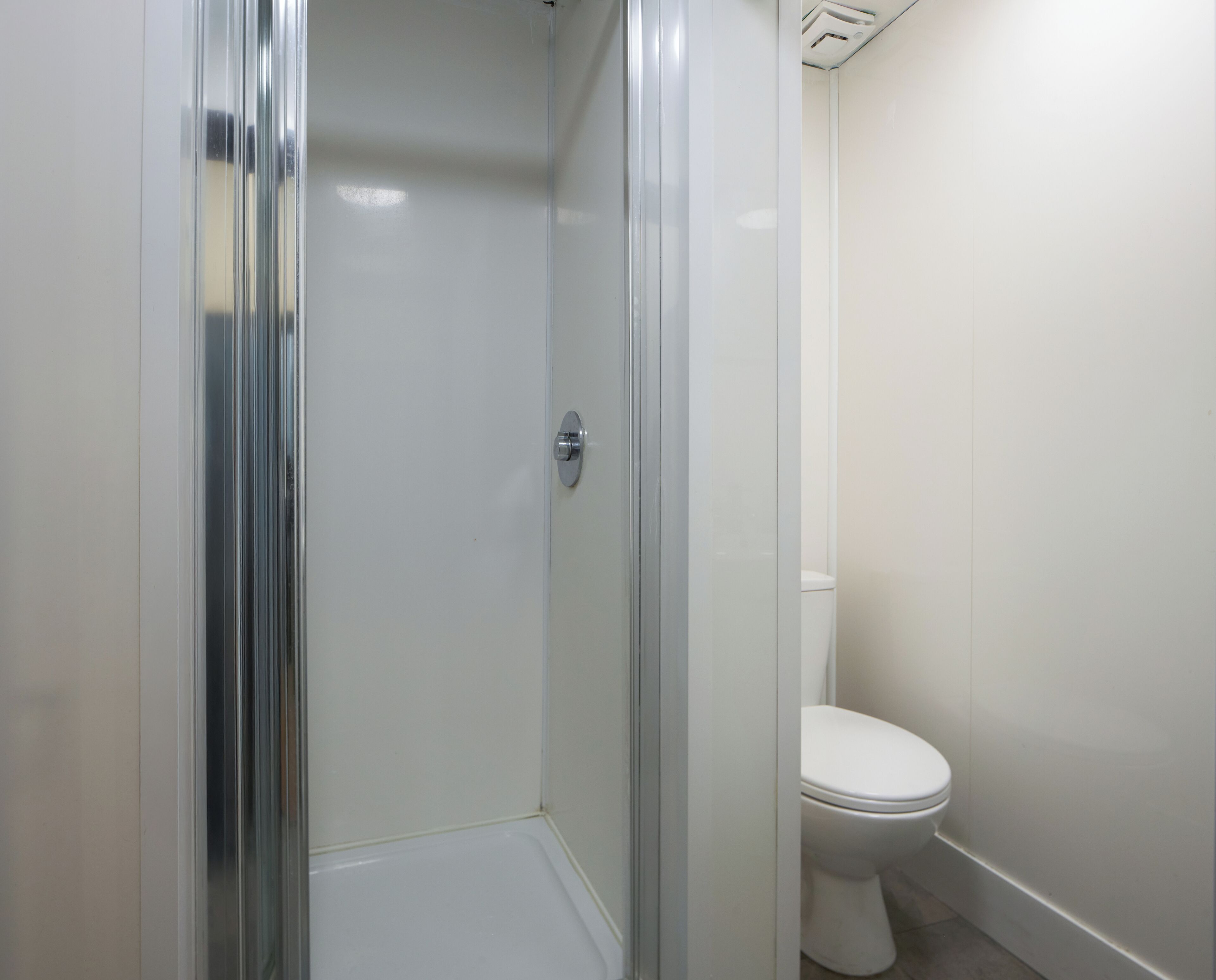 Une salle de bain avec une douche à parois de verre, des toilettes blanches et un lavabo blanc.
