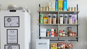Cuina amb un frigorífic blanc, un rebost blanc i prestatges plens d'una varietat d'aliments.