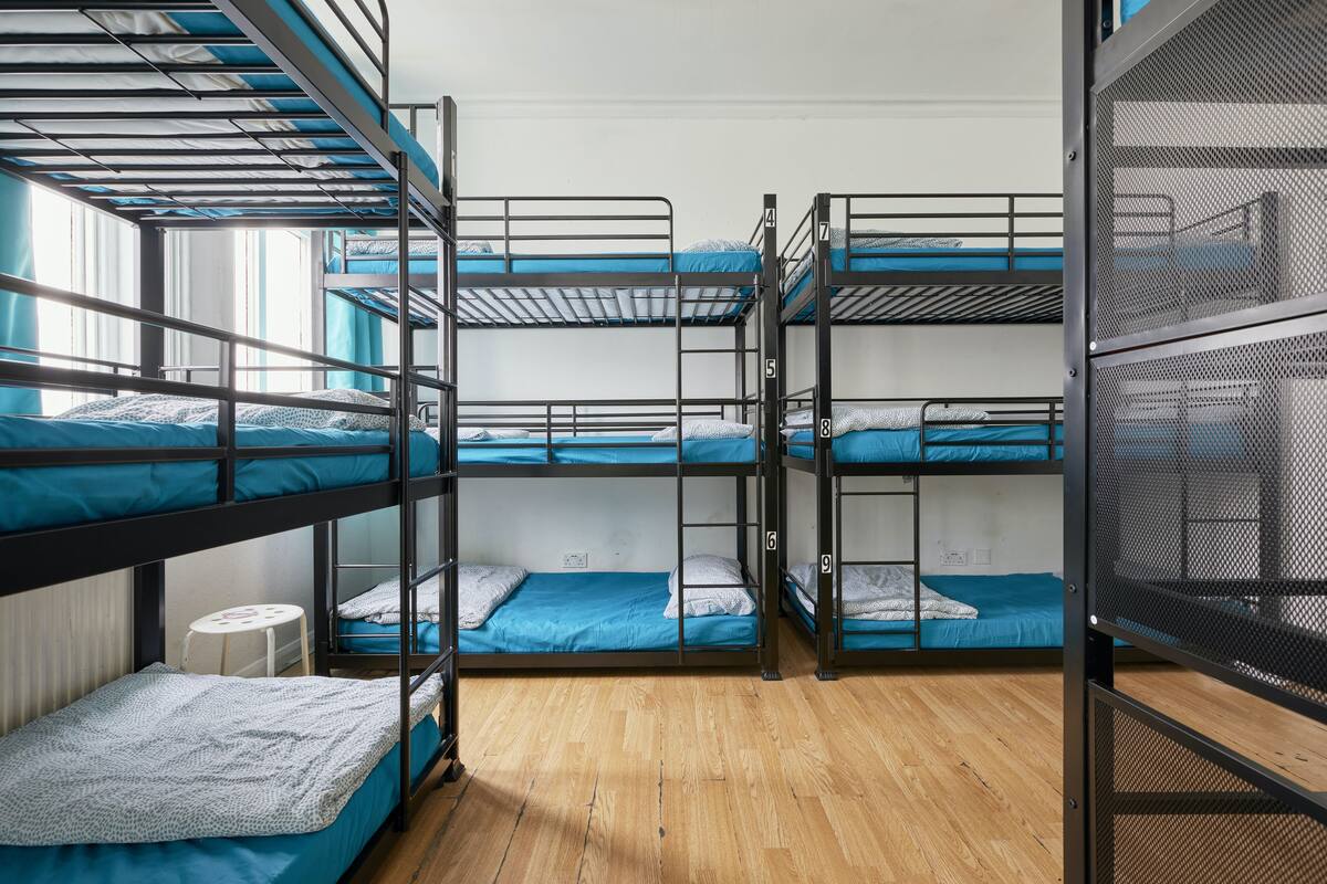 A bunk bed room with multiple beds, a small table, and a window.