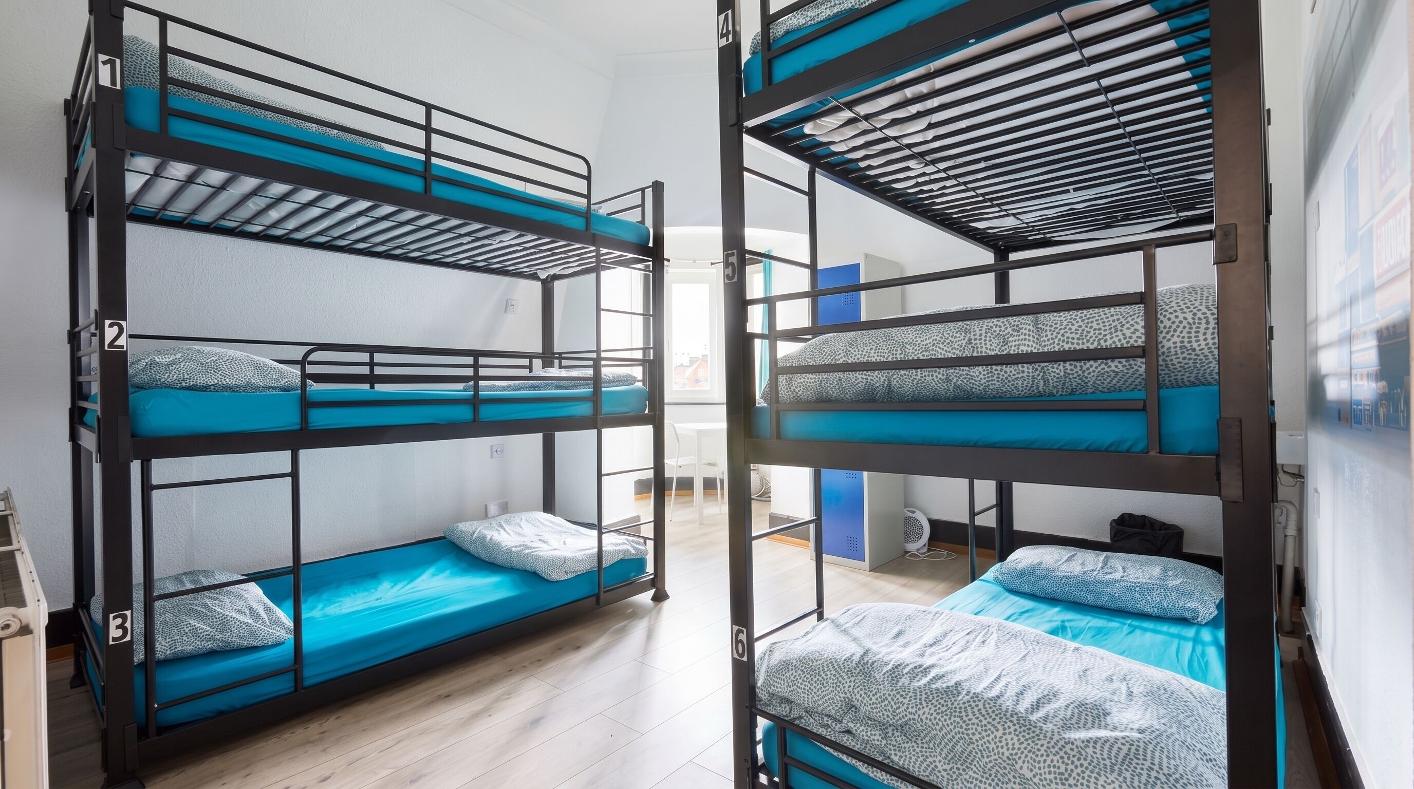 Bunk beds with numbers 1 to 6, a white chair, and a small table in a room with wooden flooring.