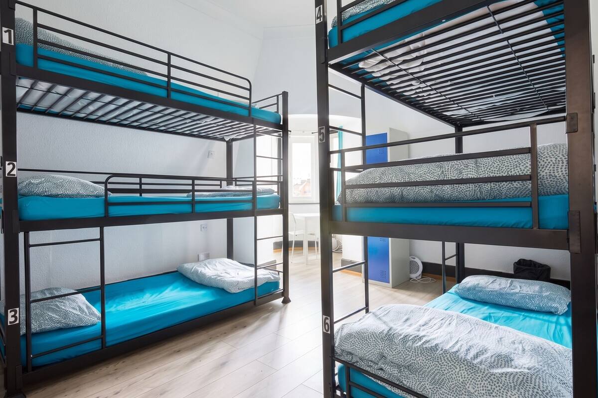 Bunk beds with numbers 1 to 6, a white chair, and a small table in a room with wooden flooring.