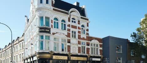 Ein historisches Gebäude mit mehreren Gewerbebetrieben im Erdgeschoss, darunter ein Hotel und eine Jugendherberge.