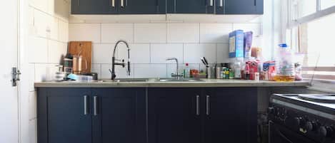 A kitchen with dark cabinets, a stainless steel sink, and a stove.