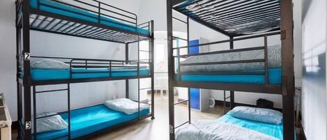 Dos literas con ropa de cama azul en una habitación con suelo de madera.