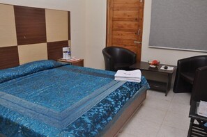 A hotel room with a bed, two chairs, a desk, and a wooden door.