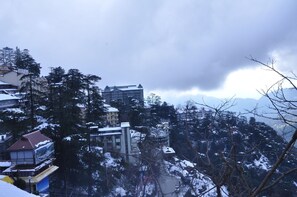 A mountainous area with buildings, some covered in snow, and a cloudy sky. - Hotel Prestige (Shimla)
