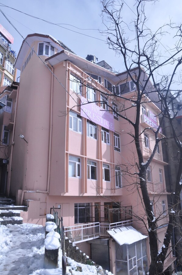 A multi-story hotel with a pink facade, balconies, and a sign indicating it is a hotel and restaurant.
