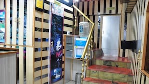 A staircase with a handrail, a water dispenser, and a poster on the wall. - Sidharath (Shimla)