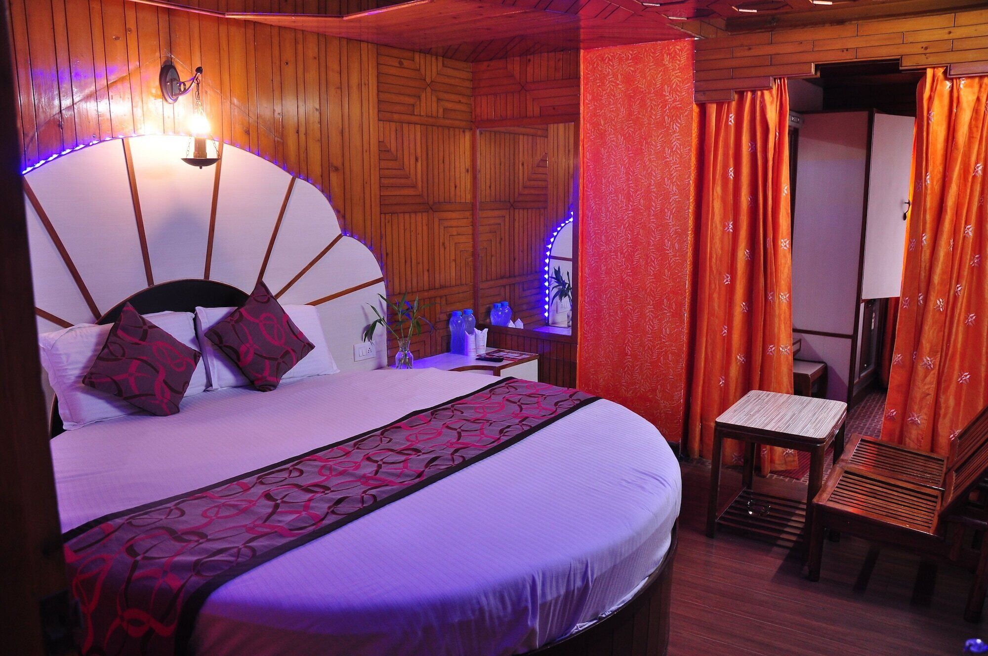 Un dormitorio con una cama grande, una mesita de noche, una silla y una ventana con cortinas.