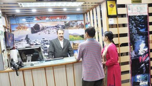 A hotel reception desk with a large poster of the hotel and a sign indicating Wi-Fi availability. - Sidharath (Shimla)