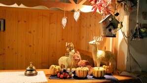 A wooden interior with a wooden table displaying a bell, a deer figurine, and pumpkins.