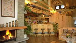 A cozy interior with a fireplace, wooden beams, a bar area, and a stone fireplace.
