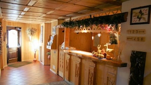 A wooden interior with a reception desk, a fireplace, and a clock on the wall.