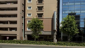Un immeuble à plusieurs étages, avec une enseigne indiquant « Toyoko Inn » et un logo représentant « SAKURA ».
