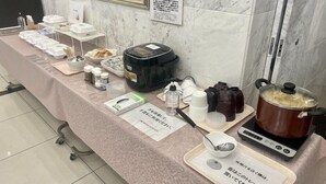 Un buffet avec divers plats et accompagnements disposés sur une table, un réchaud portable et un panneau indiquant les instructions.