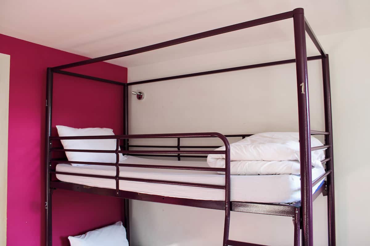 A bunk bed with white bedding in a room with a red accent wall.