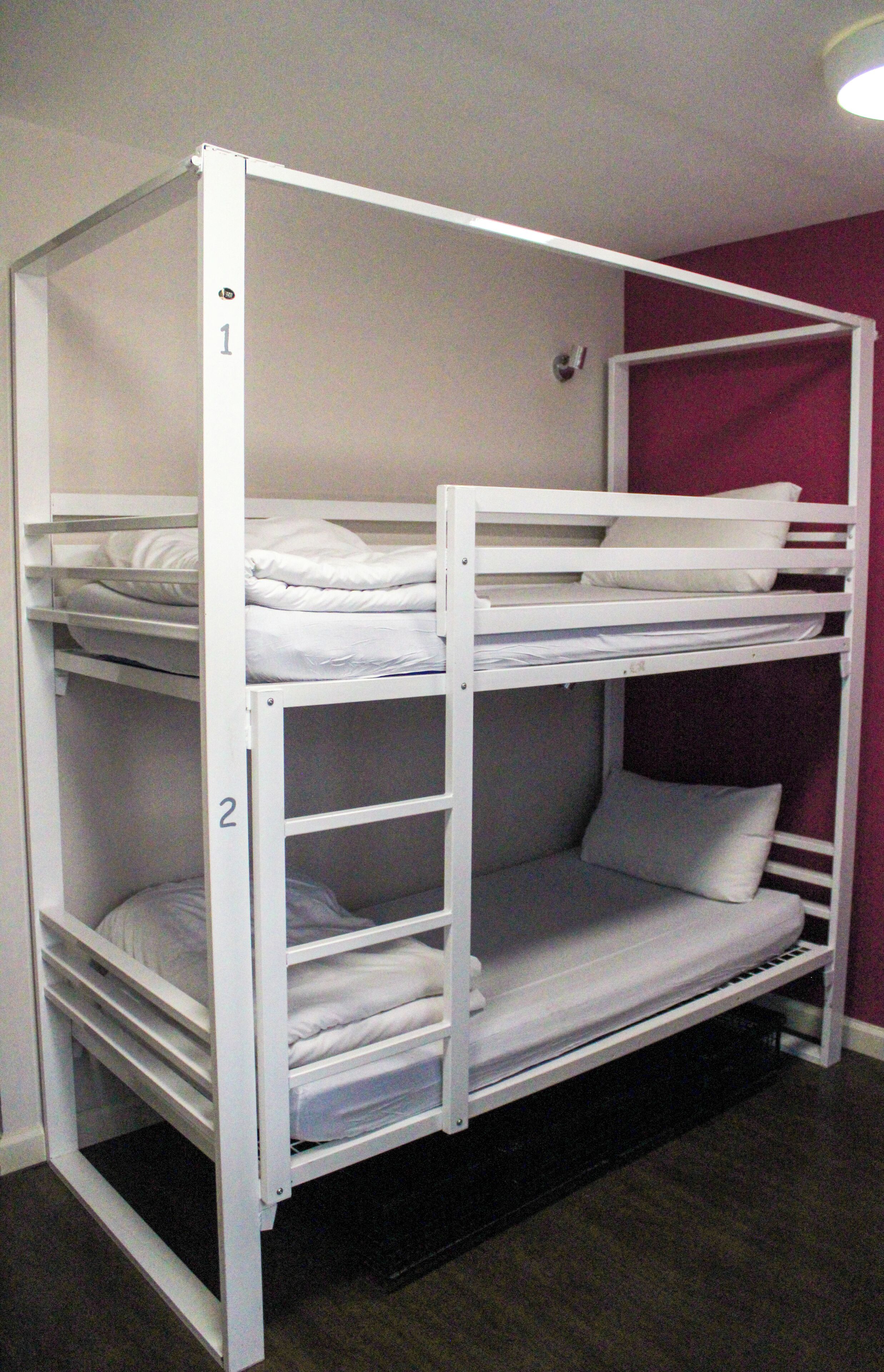 A bunk bed with two levels, each with a mattress and pillows.