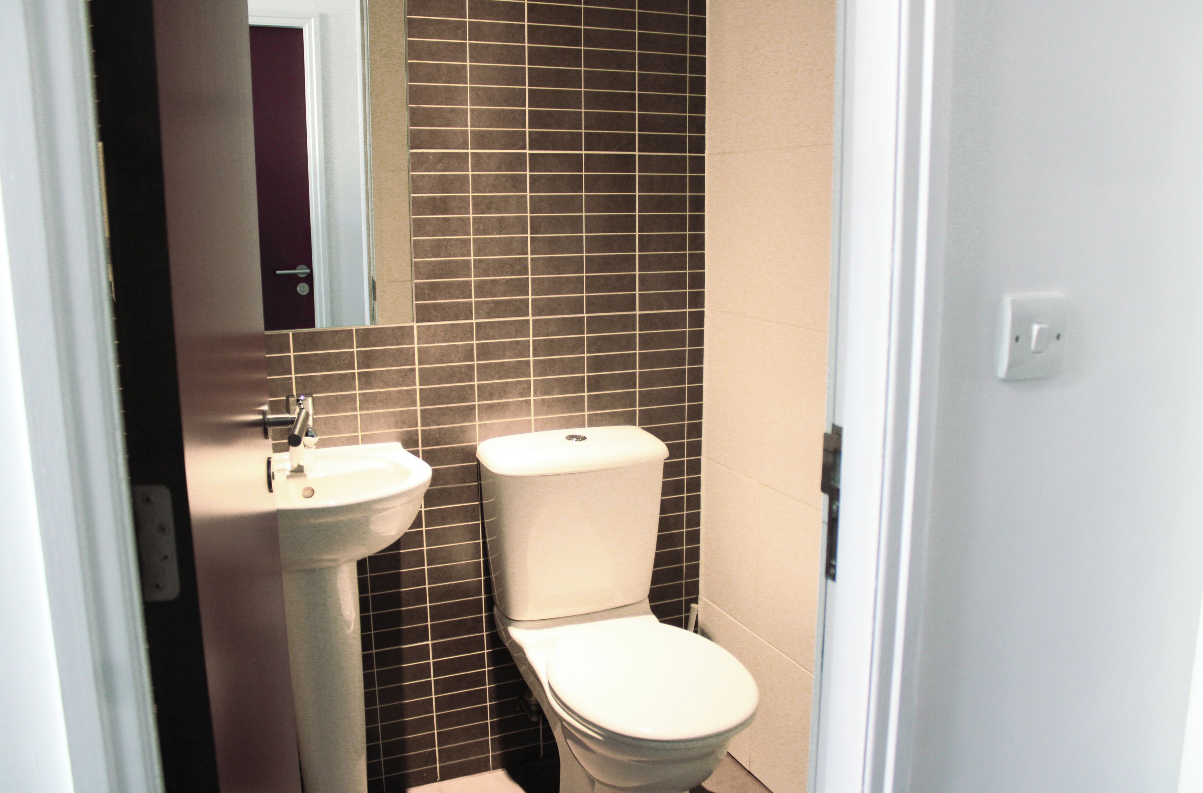 Een badkamer met een witte wastafel, een toilet en een spiegel boven de wastafel.