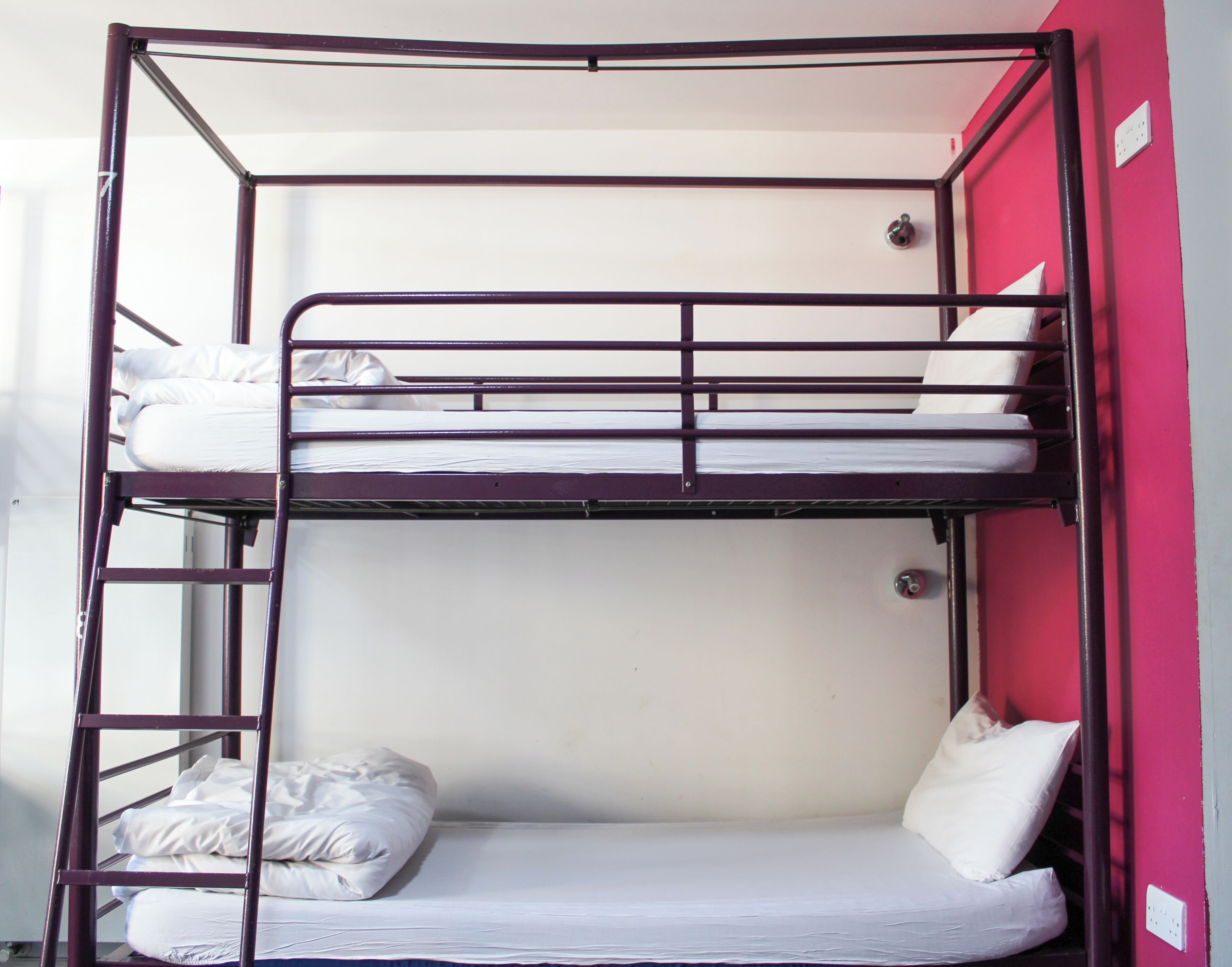A bunk bed with white bedding and a ladder.