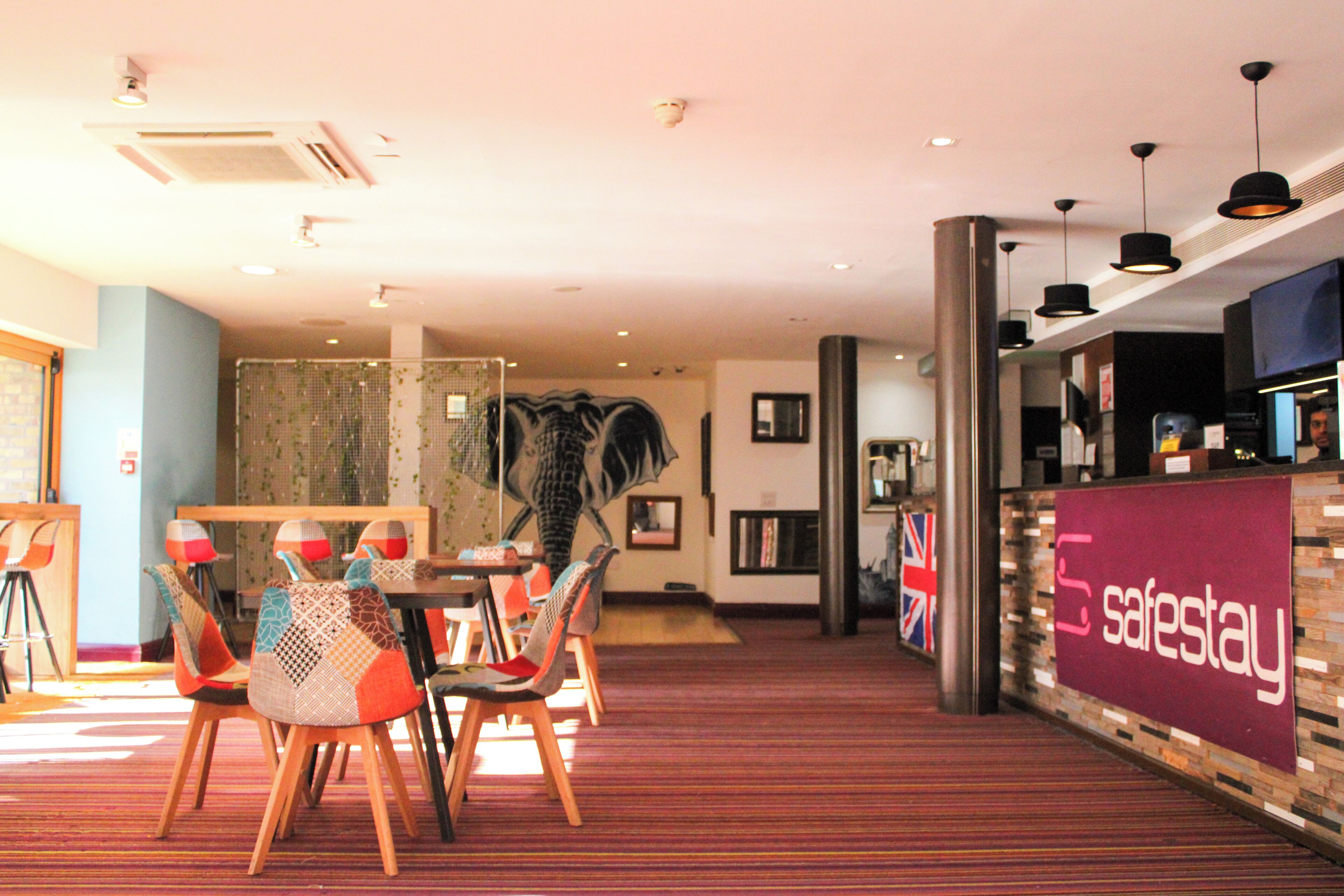 A hotel lobby with a reception desk, chairs, and a patterned wall.