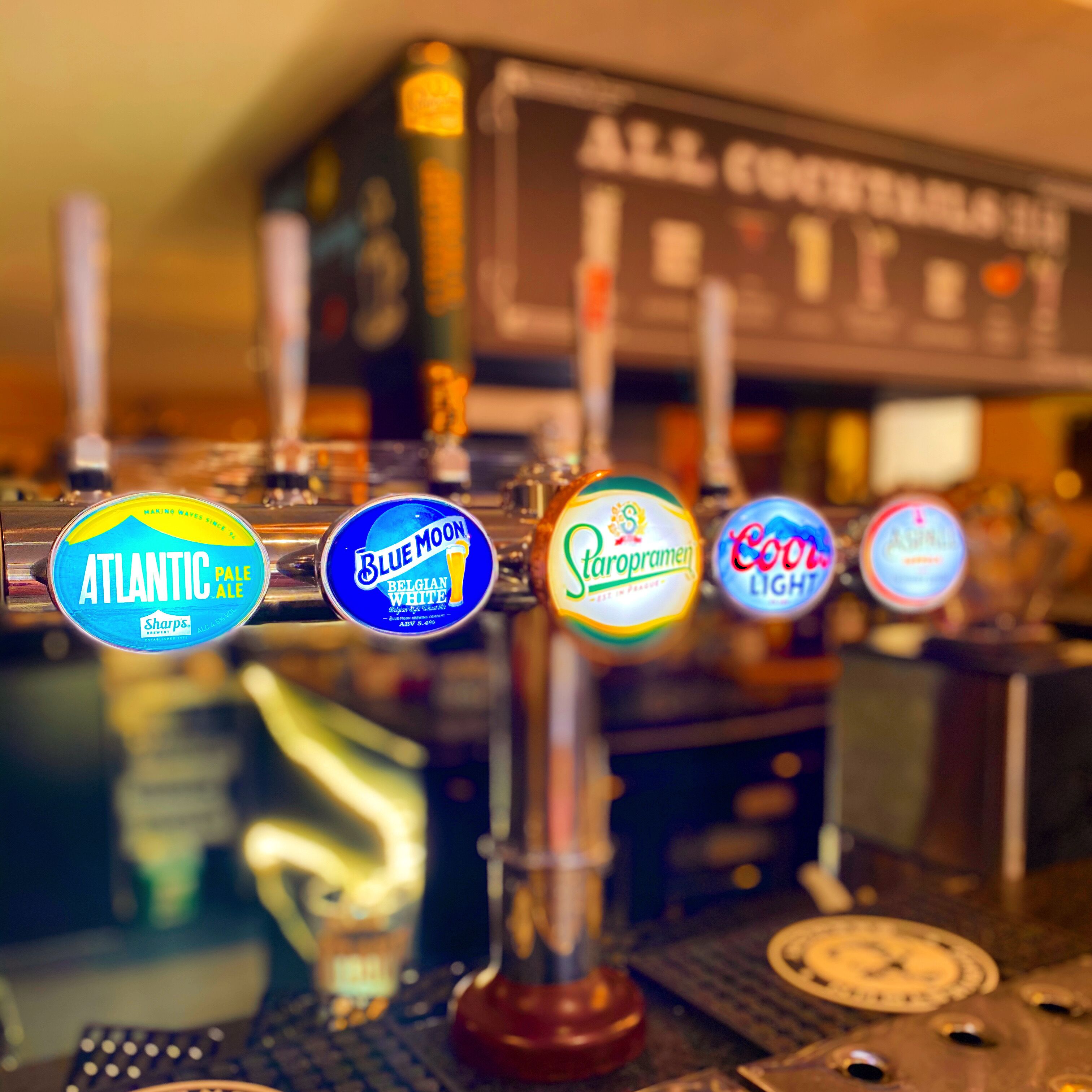 A bar with various beer taps including brands like Atlantic Pale Ale, Blue Moon Belgian White, Staropramen, and Coors Light.