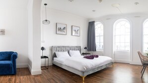 A bedroom with a large bed, a blue armchair, and a window with a view. - Safestay London Elephant & Castle (London)