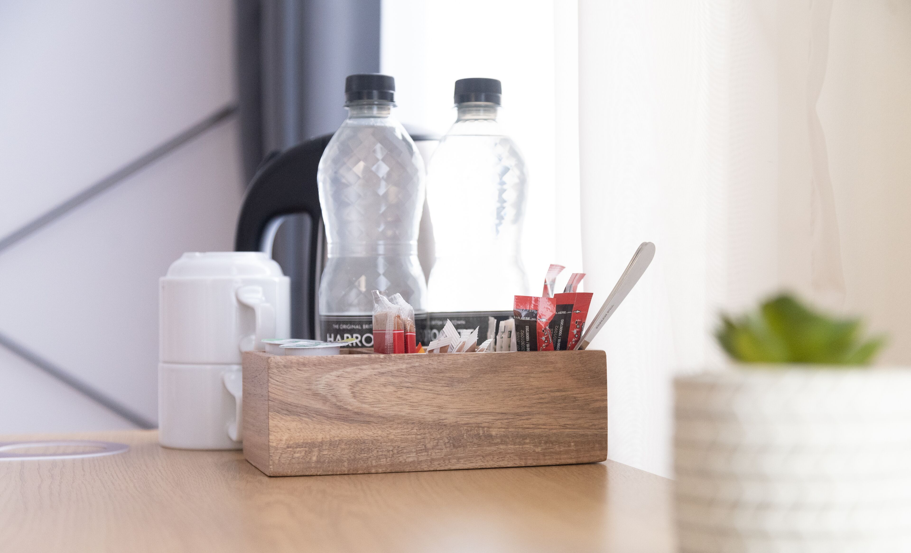 Un plateau en bois contenant des articles de papeterie et deux bouteilles d’eau, posé sur une table.