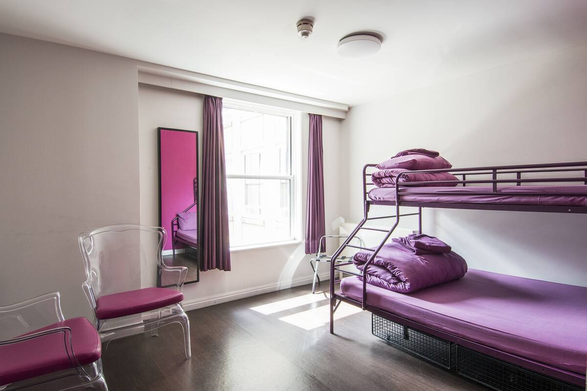 A bunk bed room with a window, a chair, and a mirror.