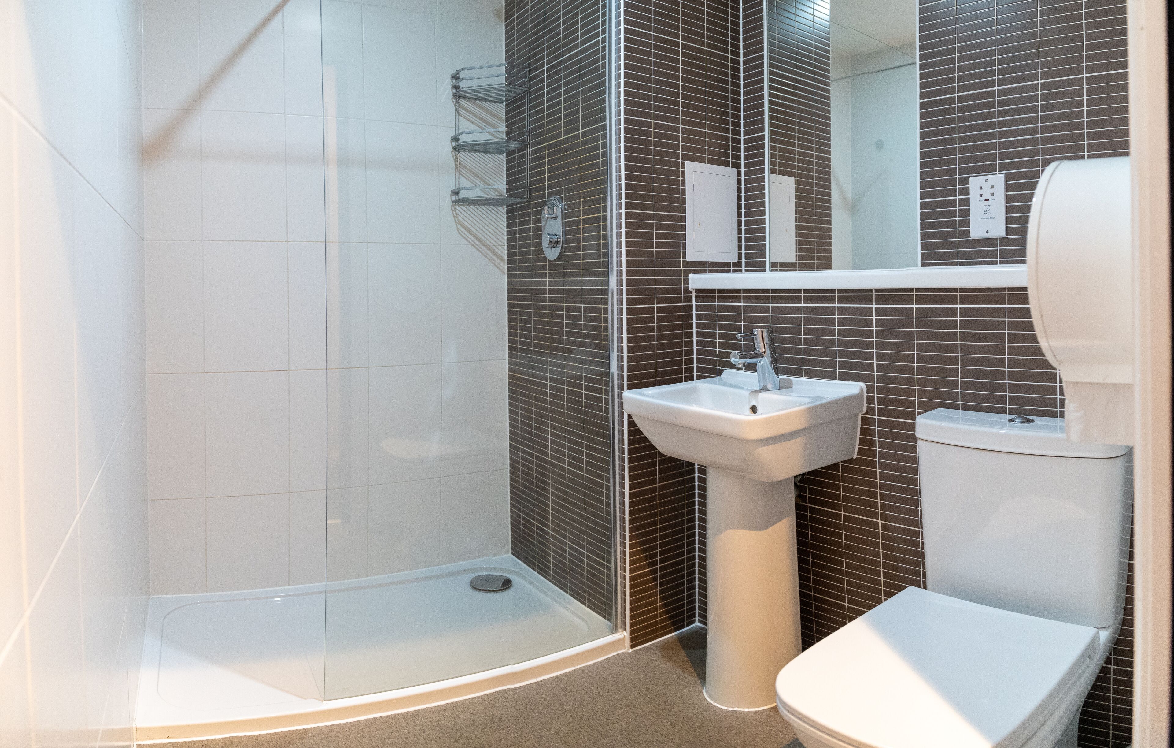 A modern bathroom with a glass shower enclosure, a pedestal sink, and a toilet.