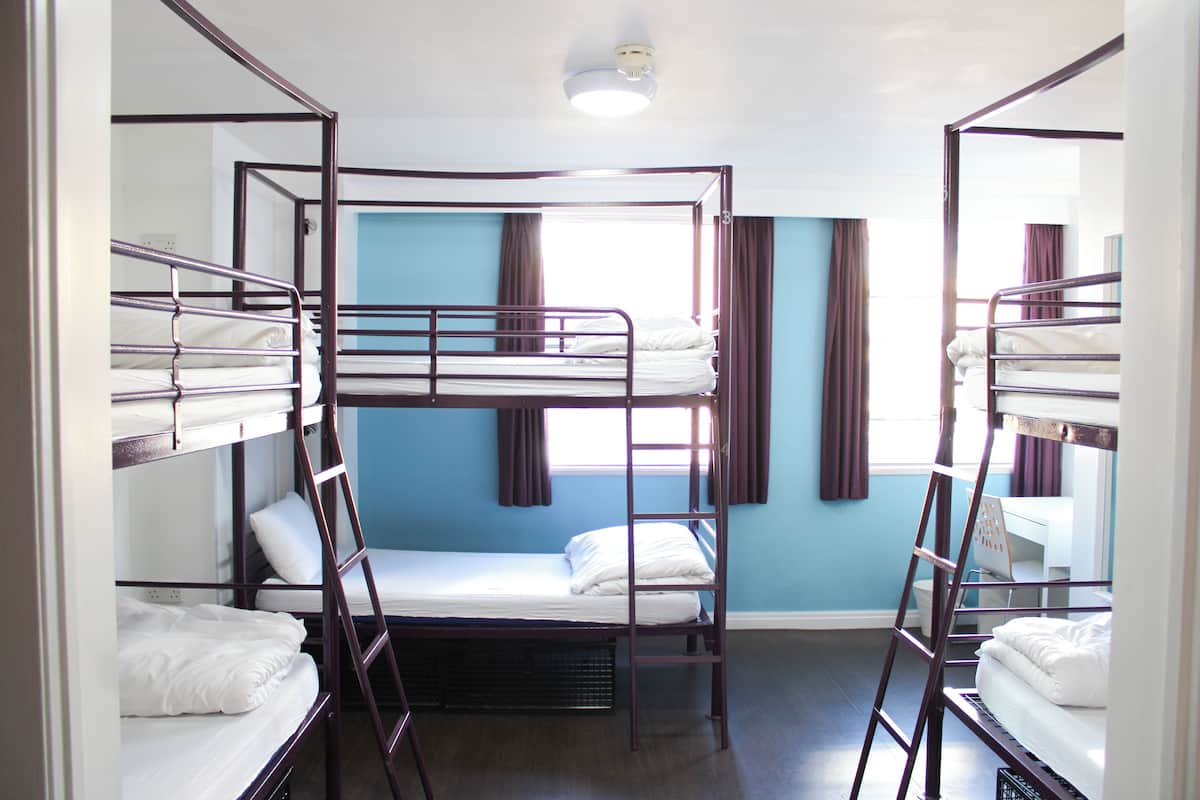 A room with bunk beds, a desk, and a window with curtains.
