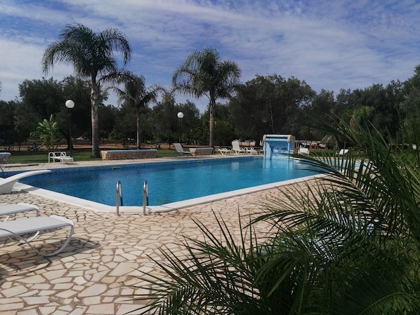 Una piscina al aire libre, una piscina con cascada, sombrillas